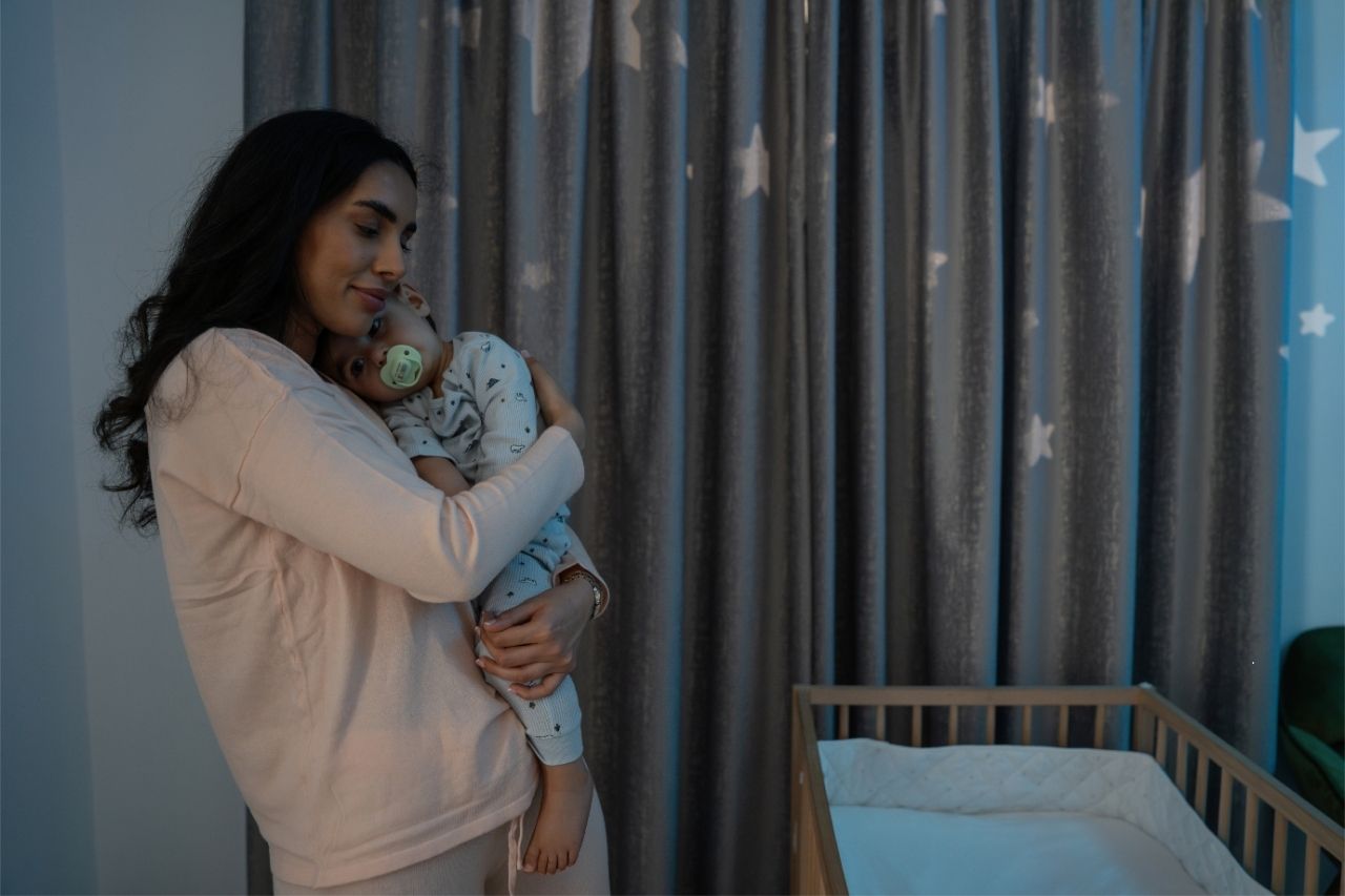 Mother cuddling her baby at night, creating a soothing and comforting bedtime routine