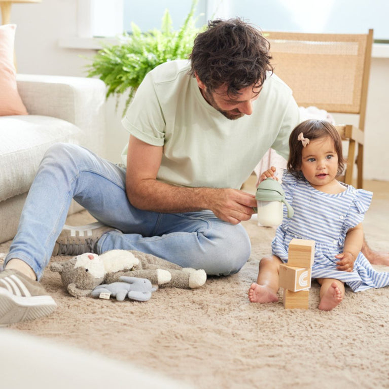 Father giving a sippy cup of milk to daughter