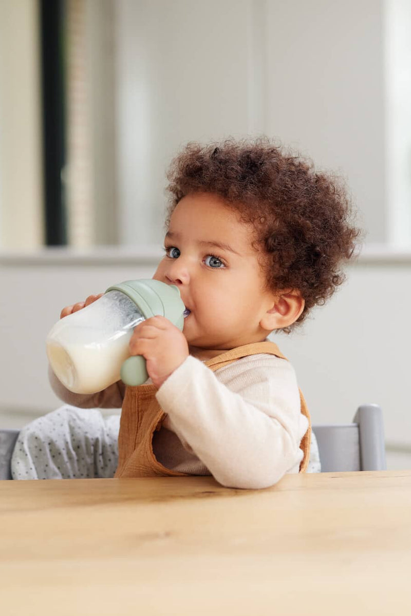 baby holding a feeding bottle filled with milk